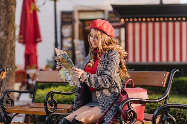 Jolie femme aux cheveux longs avec une coiffure frisée en regardant le plan de la ville avec intérêt