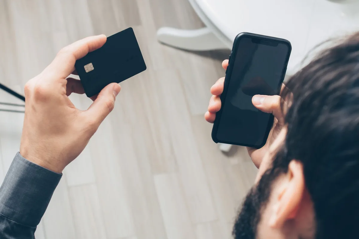 Personne tenant une carte bancaire et un smartphone