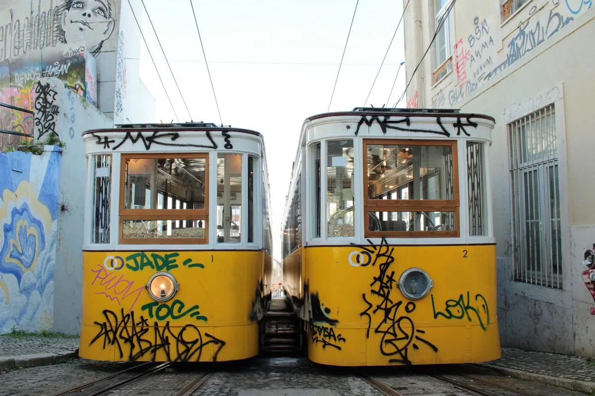 Deux tramways jaunes de Lisbonne dans une rue étroite