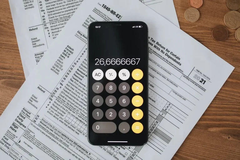 Calculatrice sur un smartphone posée sur des formulaires fiscaux