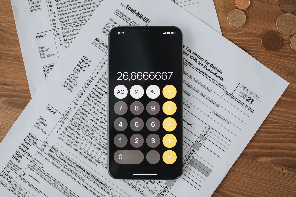 Calculatrice sur un smartphone posée sur des formulaires fiscaux
